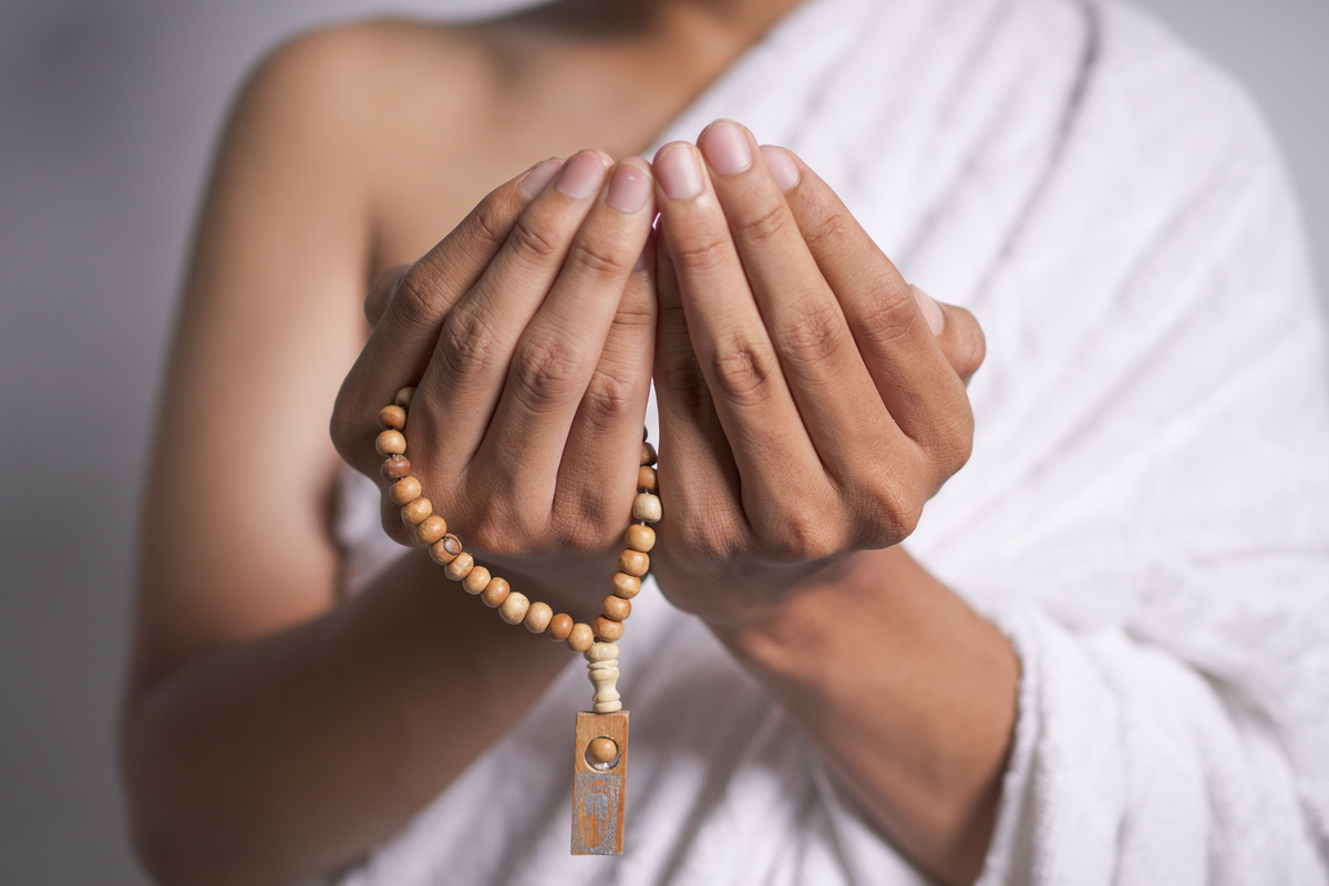 muslim man wear ihram clothes was prayer and hold praying beads