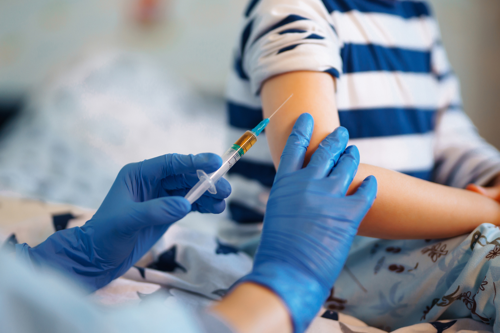 Childhood vaccination. Children's doctor vaccinating little boy at home.